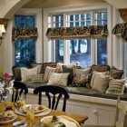 Столовая, традиционный стиль, встроенный диван-кладовка под окном, подушки с разноцветным текстилем, деревянный стол, сервиз